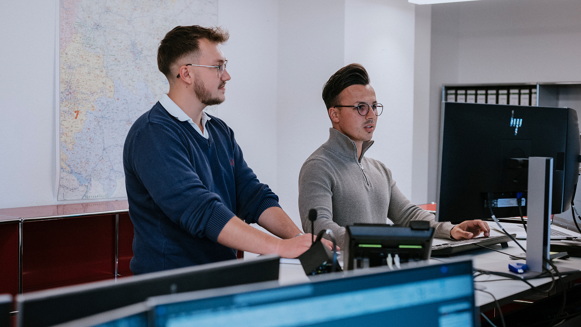 Zwei Männer stehen an einem Schreibtisch