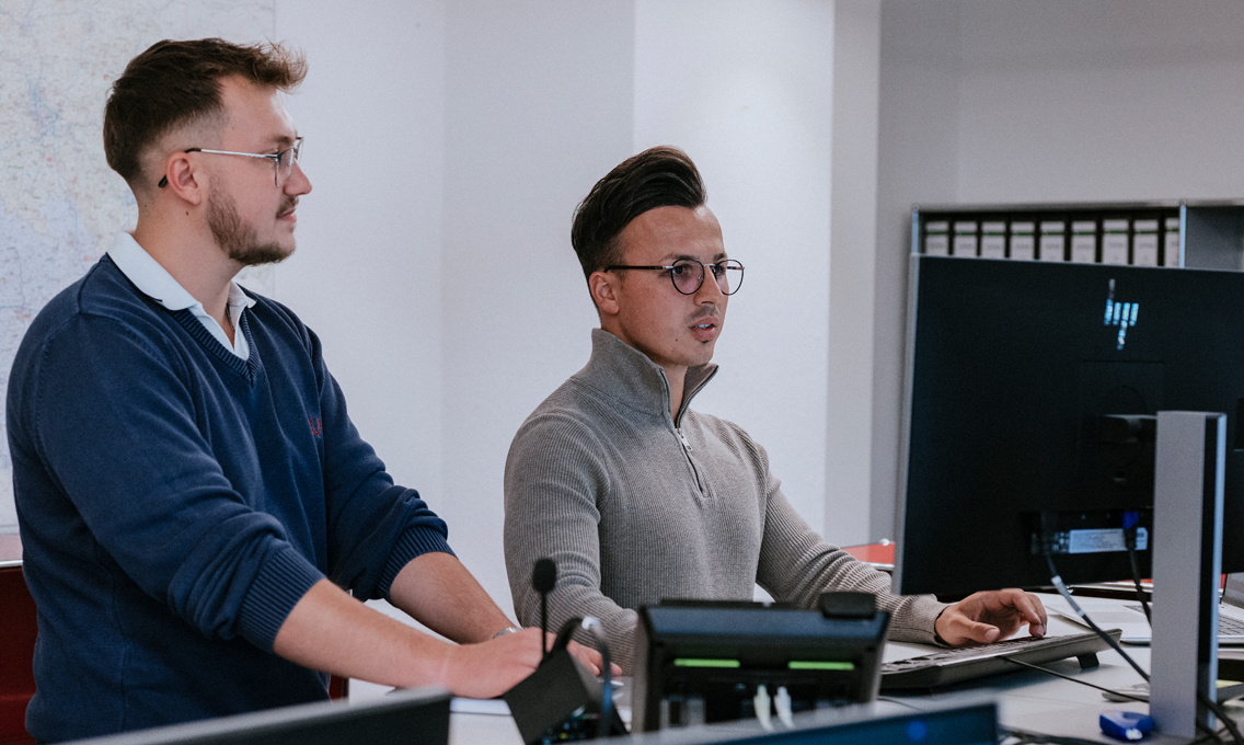 Zwei Männer stehen an einem Schreibtisch